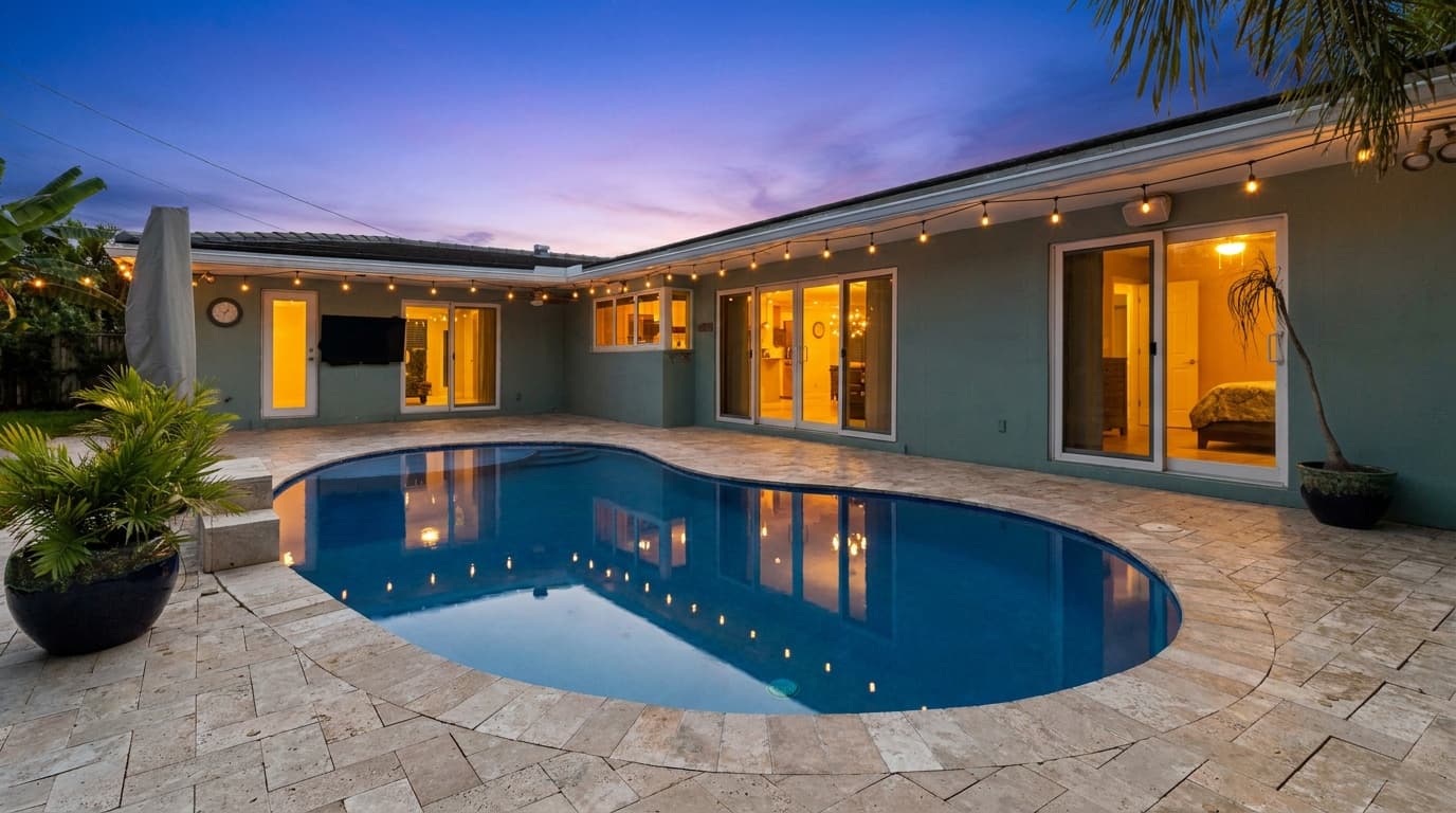 Backyard pool at dusk with the existing string lights along the roofline switched on