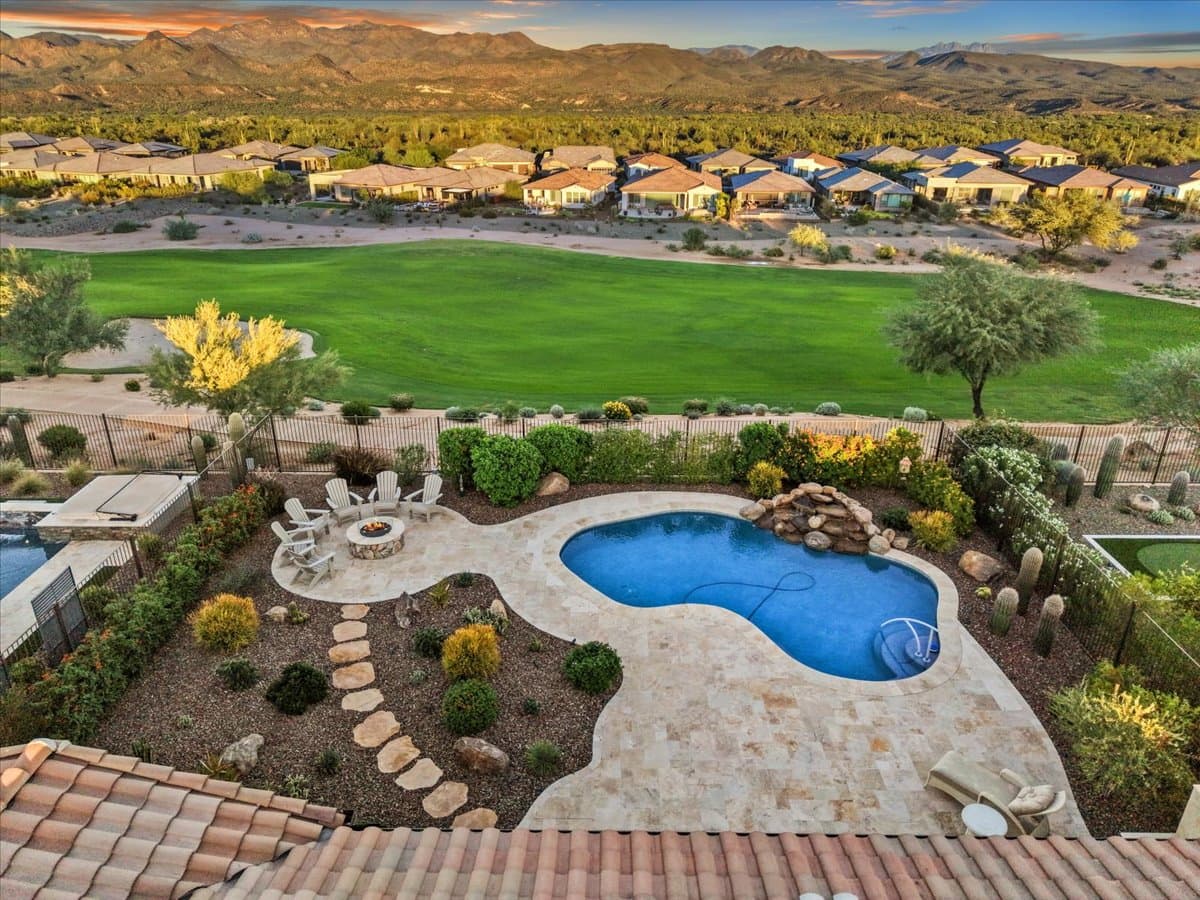 Elevated view over a backyard pool toward a golf course and a row of houses beyond